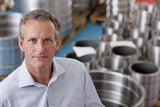 Photo: Close up portrait of confident businessman among steel roller bearings in manufacturing plant Close up portrait of confident businessman among steel roller bearings in manufacturing plant