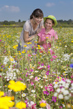 Photo: Portrait of smiling grandmother and granddaughter standing among wildflowers in sunny meadow Portrait of smiling grandmother and granddaughter standing among wildflowers in sunny meadow