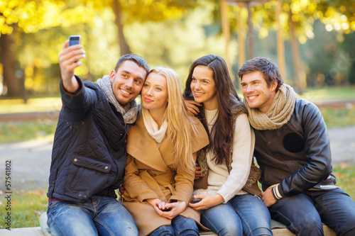 Photo: group of friends with photo camera in autumn park group of friends with photo camera in autumn park