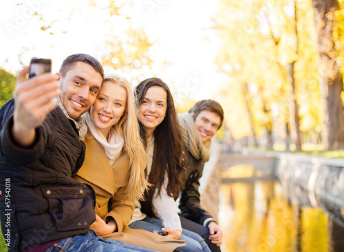 Photo: group of friends with photo camera in autumn park group of friends with photo camera in autumn park