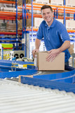 Foto: Portrait of smiling worker with cardboard box on production line in distribution warehouse Portrait of smiling worker with cardboard box on production line in distribution warehouse