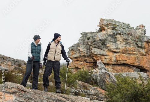 Photo: Couple on rocky landscape with trekking poles against sky Couple on rocky landscape with trekking poles against sky