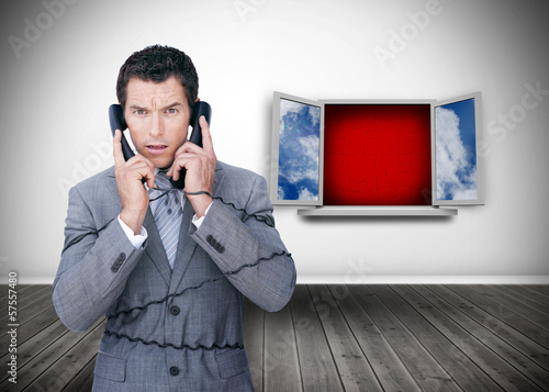Photo: Angry businessman wrapped in cables phoning Angry businessman wrapped in cables phoning