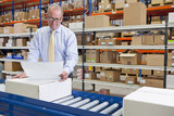 Photo: Supervisor examining paperwork and boxes on production line in distribution warehouse Supervisor examining paperwork and boxes on production line in distribution warehouse