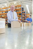 Foto: Portrait of smiling supervisor leaning on box on production line in distribution warehouse Portrait of smiling supervisor leaning on box on production line in distribution warehouse