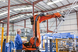 Photo: Worker controlling robotic machinery lifting steel fencing on production line in manufacturing plant Worker controlling robotic machinery lifting steel fencing on production line in manufacturing plant