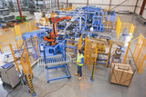 Photo: Worker controlling robotic machinery lifting steel fencing on production line in manufacturing plant Worker controlling robotic machinery lifting steel fencing on production line in manufacturing plant