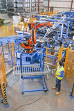 Photo: Worker controlling robotic machinery lifting steel fencing on production line in manufacturing plant Worker controlling robotic machinery lifting steel fencing on production line in manufacturing plant