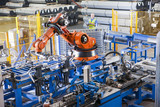 Photo: Worker controlling robotic machinery lifting steel fencing on production line in manufacturing plant Worker controlling robotic machinery lifting steel fencing on production line in manufacturing plant