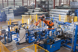 Photo: Worker controlling robotic machinery lifting steel fencing on production line in manufacturing plant Worker controlling robotic machinery lifting steel fencing on production line in manufacturing plant