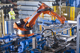 Foto: Worker controlling robotic machinery lifting steel fencing on production line in manufacturing plant Worker controlling robotic machinery lifting steel fencing on production line in manufacturing plant