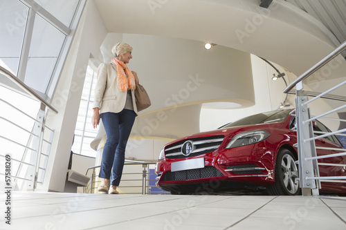 Photo: Woman looking at car in car dealership showroom Woman looking at car in car dealership showroom