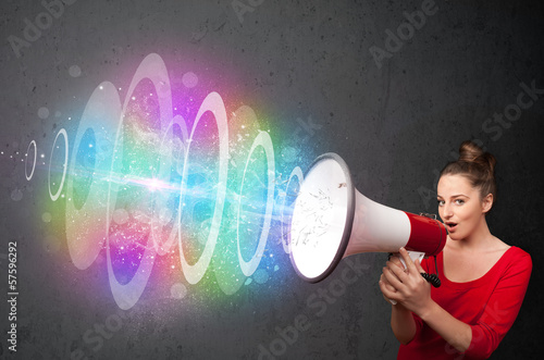 Photo: Young girl yells into a loudspeaker and colorful energy beam com Young girl yells into a loudspeaker and colorful energy beam com