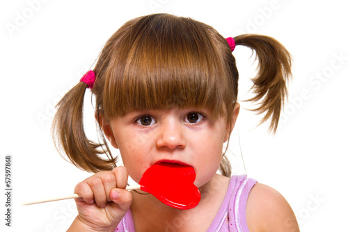 Photo: little girl eating red heart lollipop little girl eating red heart lollipop