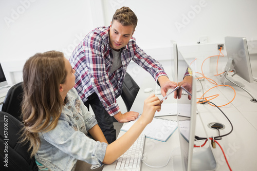 Photo: Two happy students working on computer pointing at it Two happy students working on computer pointing at it