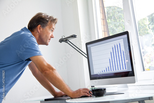 Photo: Mann schaut sich am Computer Statistik an Mann schaut sich am Computer Statistik an
