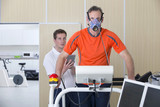 Photo: Sports scientist with digital tablet monitoring runner with mask on treadmill in laboratory Sports scientist with digital tablet monitoring runner with mask on treadmill in laboratory