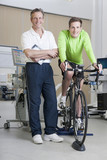 Photo: Portrait of confident sports scientist and cyclist on exercise bike in laboratory Portrait of confident sports scientist and cyclist on exercise bike in laboratory