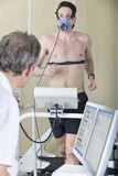 Photo: Sports scientist at computer watching runner with mask on treadmill in laboratory Sports scientist at computer watching runner with mask on treadmill in laboratory