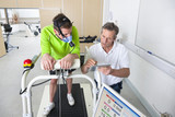Photo: Sports scientist and runner with mask on treadmill looking down at digital tablet in laboratory Sports scientist and runner with mask on treadmill looking down at digital tablet in laboratory