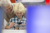 Photo: Smiling grandfather and grandson looking at cell phone and digital tablet in electronics store Smiling grandfather and grandson looking at cell phone and digital tablet in electronics store