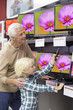 Foto: Grandfather and grandson with remote control looking at televisions in electronics store Grandfather and grandson with remote control looking at televisions in electronics store