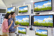 Foto: Smiling couple looking at wildflowers on flat screen televisions in electronics store Smiling couple looking at wildflowers on flat screen televisions in electronics store