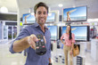 Photo: Portrait of smiling man holding remote control in front of televisions in electronics store Portrait of smiling man holding remote control in front of televisions in electronics store