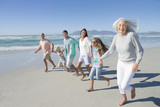 Photo: Portrait of happy multi-generation family holding hands and running on sunny beach Portrait of happy multi-generation family holding hands and running on sunny beach