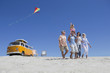 Photo: Happy multi-generation family with kite walking on sunny beach with van in background Happy multi-generation family with kite walking on sunny beach with van in background