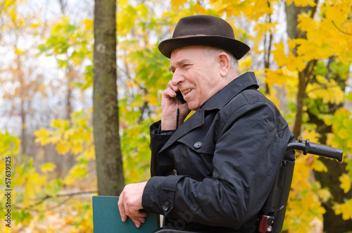 Photo: Senior man in a wheelchair chatting on his mobile Senior man in a wheelchair chatting on his mobile