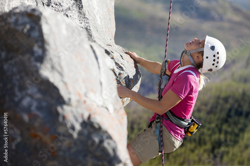 Photo: Female rock climber scaling rock face and looking up Female rock climber scaling rock face and looking up