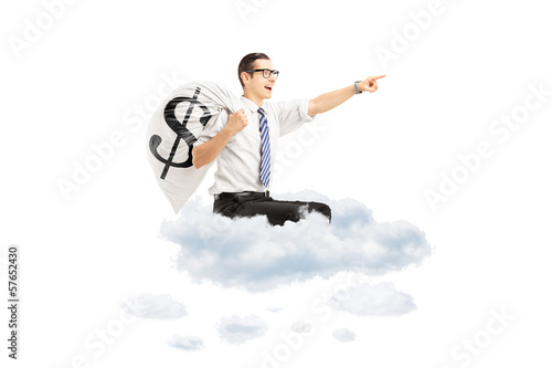 Photo: Young businessman with a money bag flying on clouds Young businessman with a money bag flying on clouds