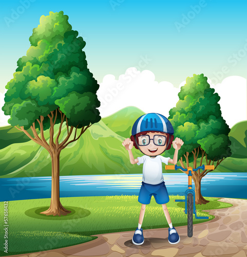 Vector: A young boy and his toy bike standing near the trees in the rive A young boy and his toy bike standing near the trees in the rive
