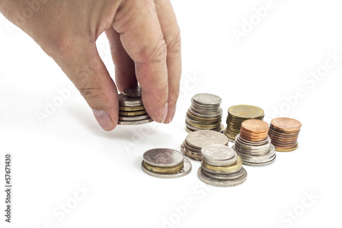 Photo: Hand holding and placing coins on the white background Hand holding and placing coins on the white background