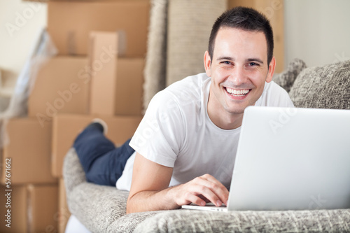 Photo: Happy man using laptop in his new home Happy man using laptop in his new home