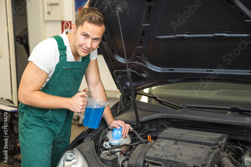 Photo: Mechanic fills coolant or cooling fluid in motor of a car Mechanic fills coolant or cooling fluid in motor of a car