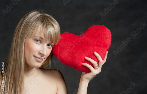 Photo: American Blond haired Woman with a Heart-Shaped Cushion on dark American Blond haired Woman with a Heart-Shaped Cushion on dark