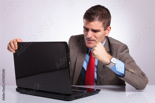 Photo: young business man wants to punch laptop young business man wants to punch laptop