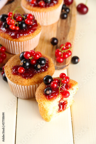 Photo: Tasty muffins with berries on white wooden table Tasty muffins with berries on white wooden table