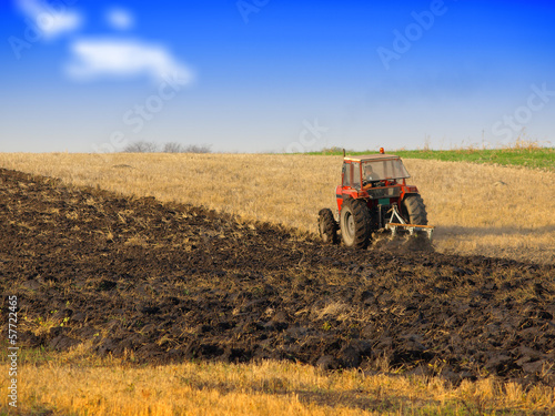 Photo: Red Tractor Plowing in Autumn Red Tractor Plowing in Autumn