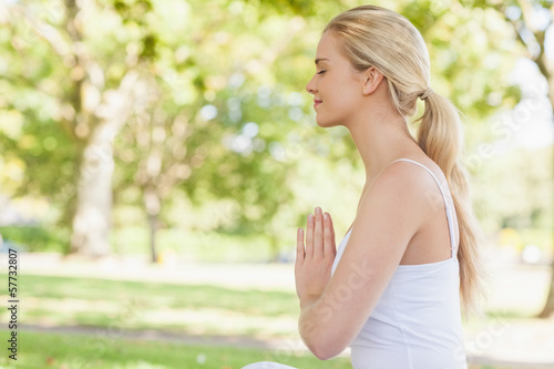 Photo: Side view of peaceful young woman meditating sitting in park Side view of peaceful young woman meditating sitting in park