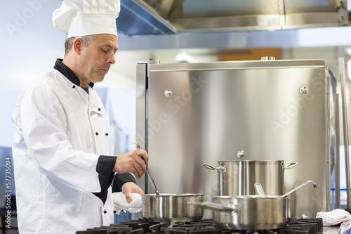 Photo: Focused head chef stirring in pot Focused head chef stirring in pot