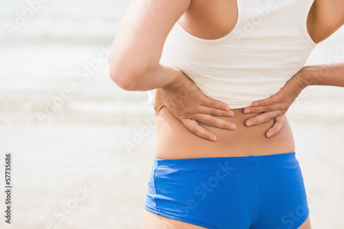 Photo: Mid section of sporty woman holding her back Mid section of sporty woman holding her back