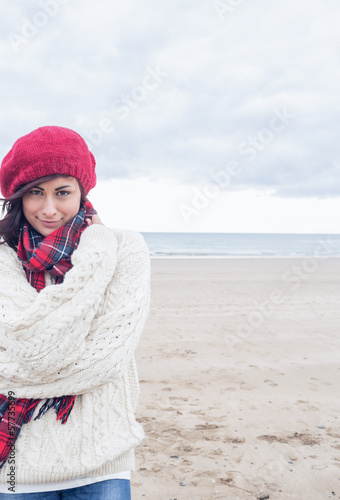 Photo: Cute smiling woman in stylish warm clothing on beach Cute smiling woman in stylish warm clothing on beach
