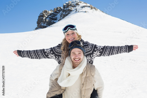 Photo: Wan piggybacking cheerful woman against snow covered hill Wan piggybacking cheerful woman against snow covered hill