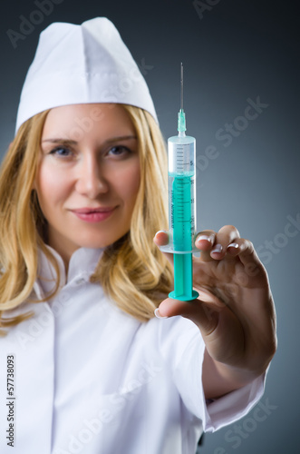 Photo: Woman doctor with syringe in dark studio Woman doctor with syringe in dark studio