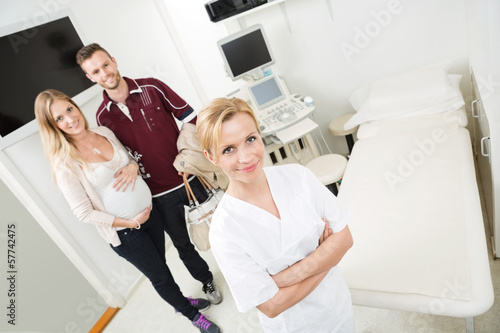 Photo: Doctor And Expectant Couple In Examination Room Doctor And Expectant Couple In Examination Room