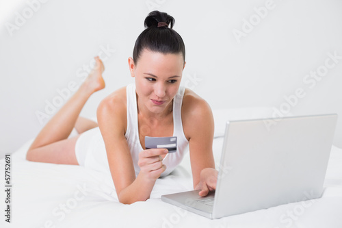 Photo: Casual woman doing online shopping in bed Casual woman doing online shopping in bed