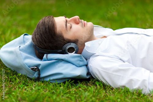 Photo: Young man listening to music lying on the grass Young man listening to music lying on the grass